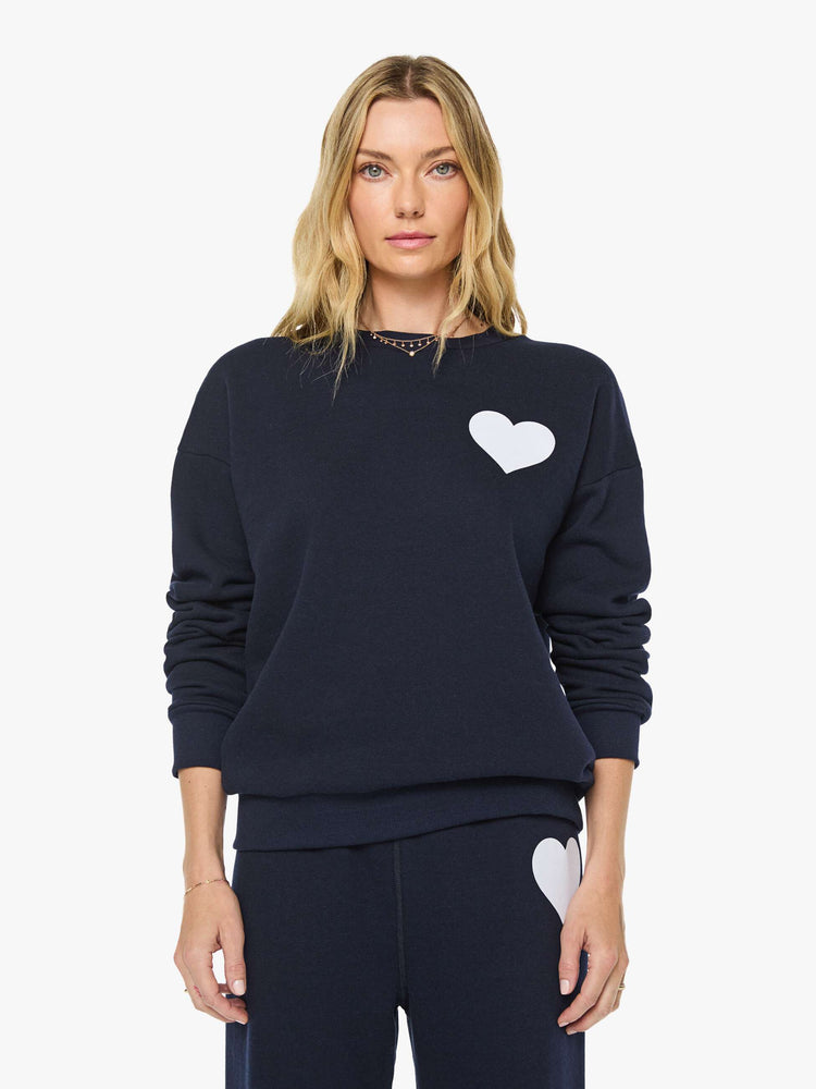 Front view of a woman in a navy with white heart sweatshirt has a crewneck, drop shoulders and a loose, comfortable fit. 