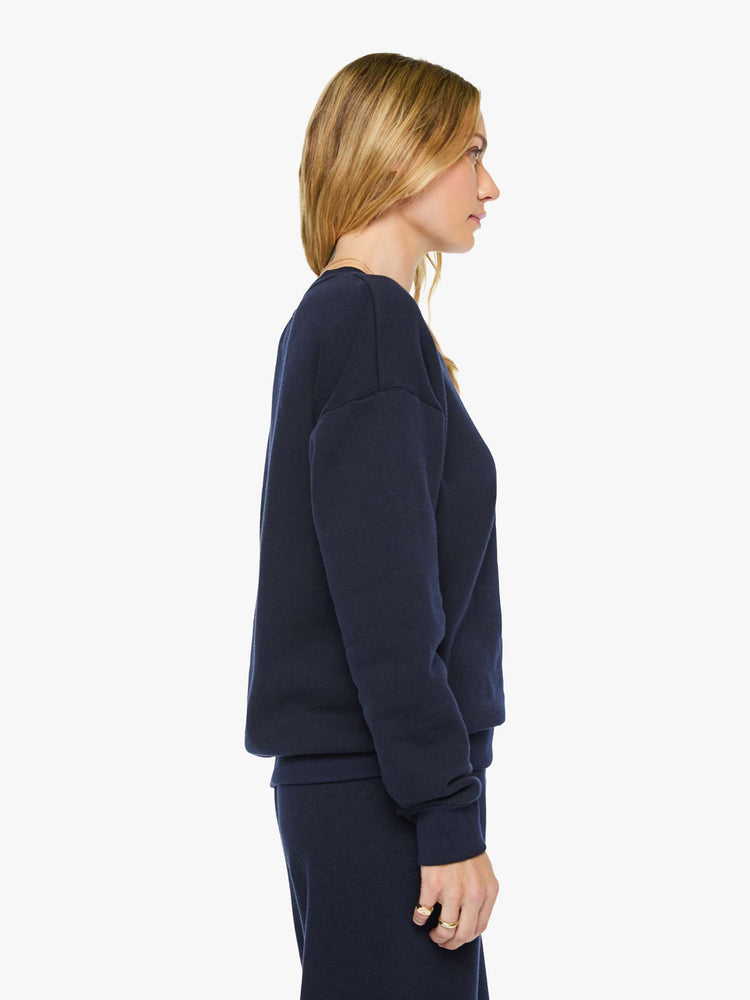 Side view of a woman in a navy with white heart sweatshirt has a crewneck, drop shoulders and a loose, comfortable fit. 