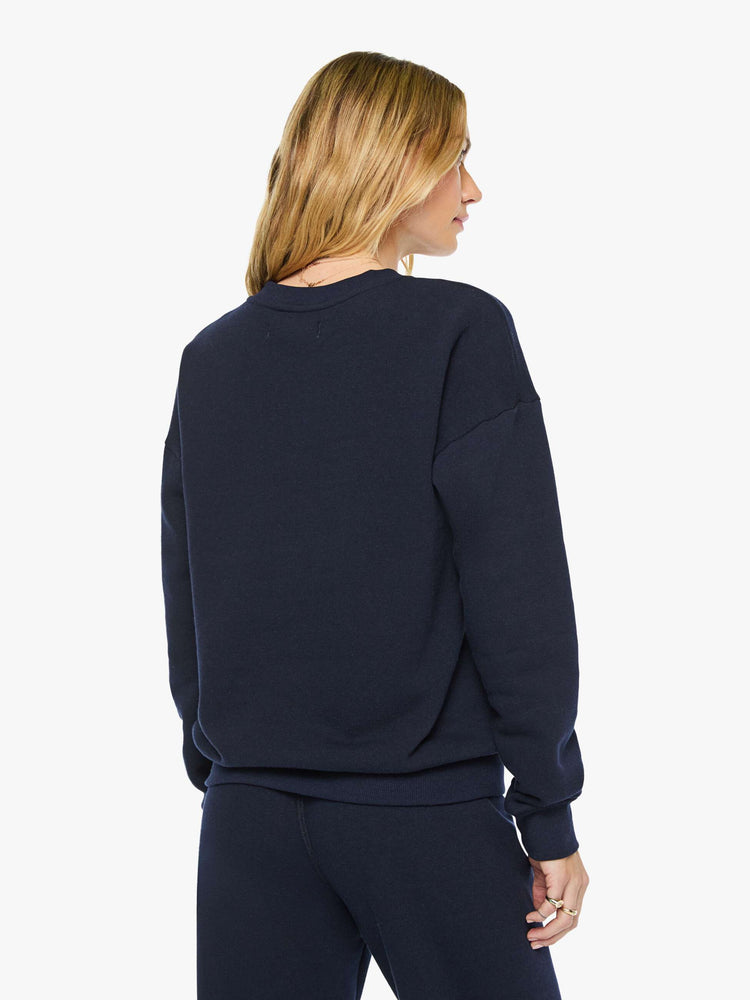 Back view of a woman in a navy with white heart sweatshirt has a crewneck, drop shoulders and a loose, comfortable fit. 