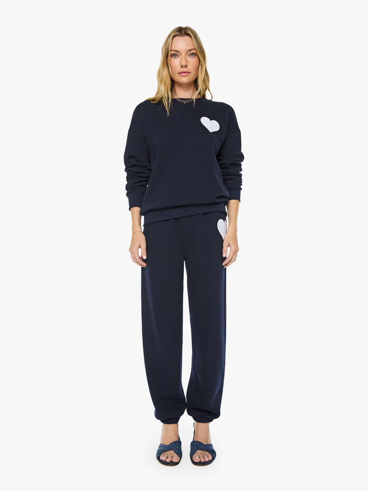 Front full body view of a woman in a navy with white heart sweatshirt has a crewneck, drop shoulders and a loose, comfortable fit. 