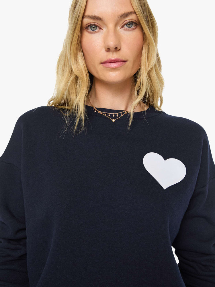 Close up view of a woman in a navy with white heart sweatshirt has a crewneck, drop shoulders and a loose, comfortable fit. 