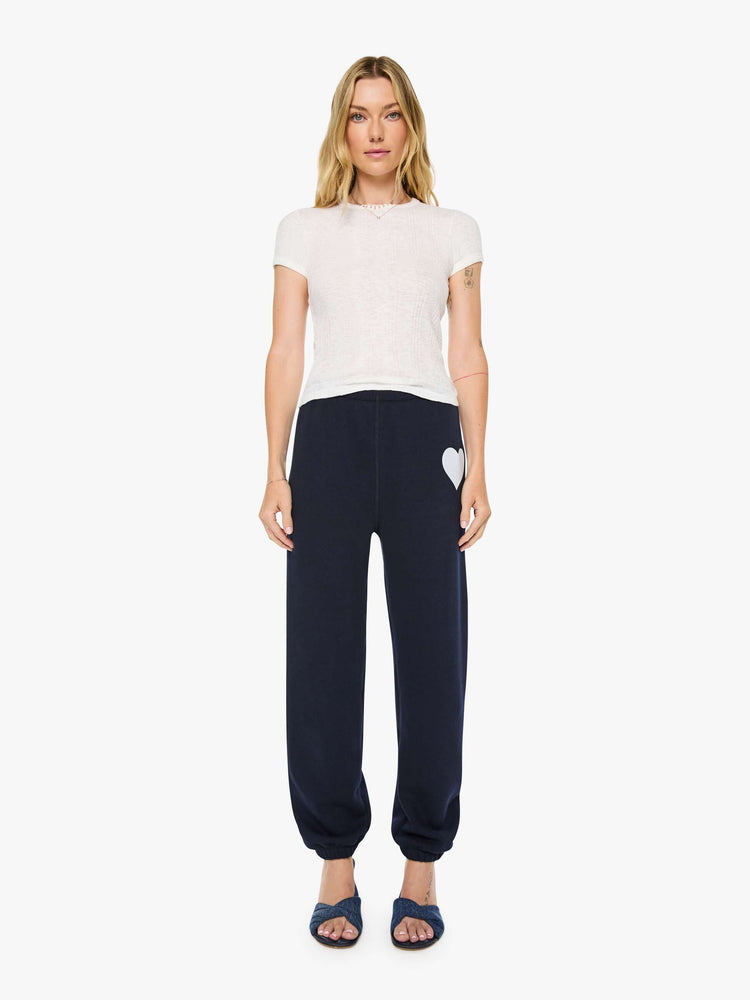 Front view of a woman in a navy with white heart on the hip sweatpants have an elastic waist and cuffs for a loose, comfortable fit.