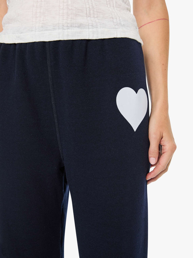 Close up view of a woman in a navy with white heart on the hip sweatpants have an elastic waist and cuffs for a loose, comfortable fit.
