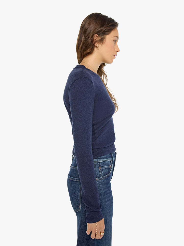 Side view of a woman in a navy baby tee with a hip-length hem, long sleeves and a semi-fitted shape.