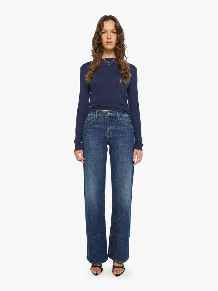 Full body view of a woman in a navy baby tee with a hip-length hem, long sleeves and a semi-fitted shape.