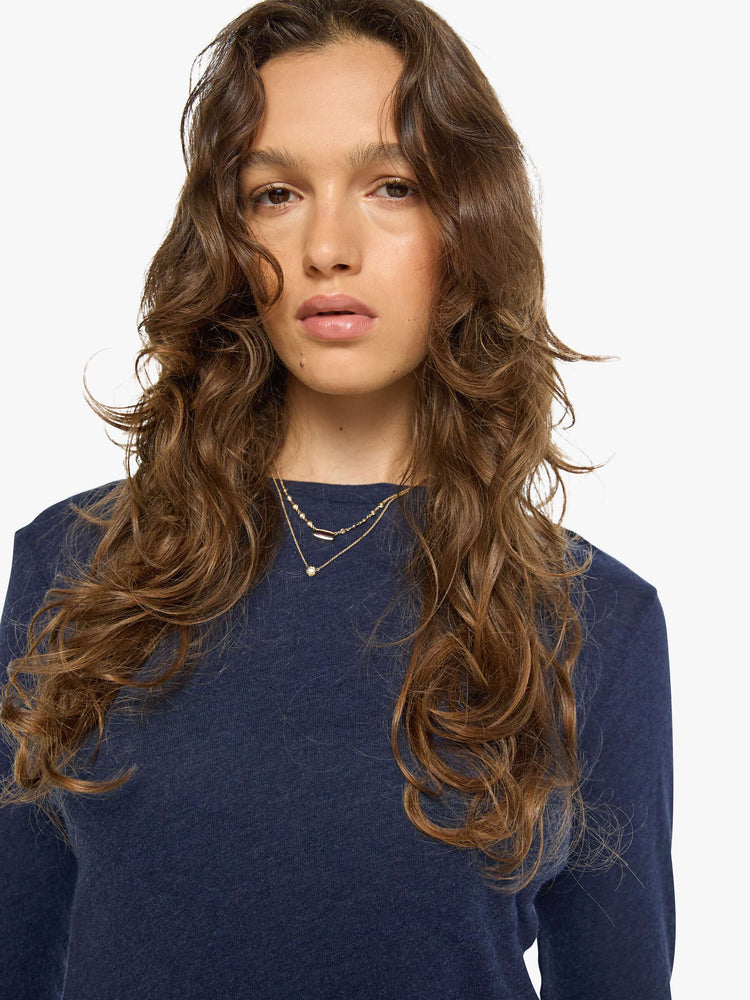 Close up view of a woman in a navy baby tee with a hip-length hem, long sleeves and a semi-fitted shape.