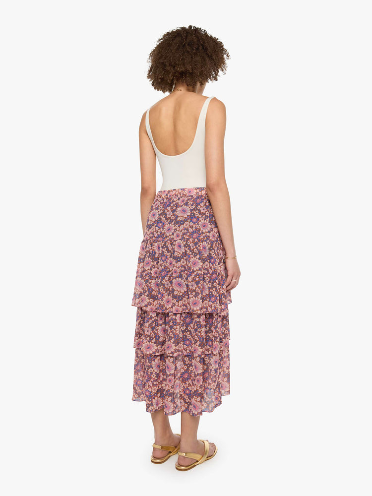 Back view of a woman in a warm-toned floral print, the Gretchen skirt features a high rise, calf-grazing hem, oversized tiers and a loose, flowy fit.