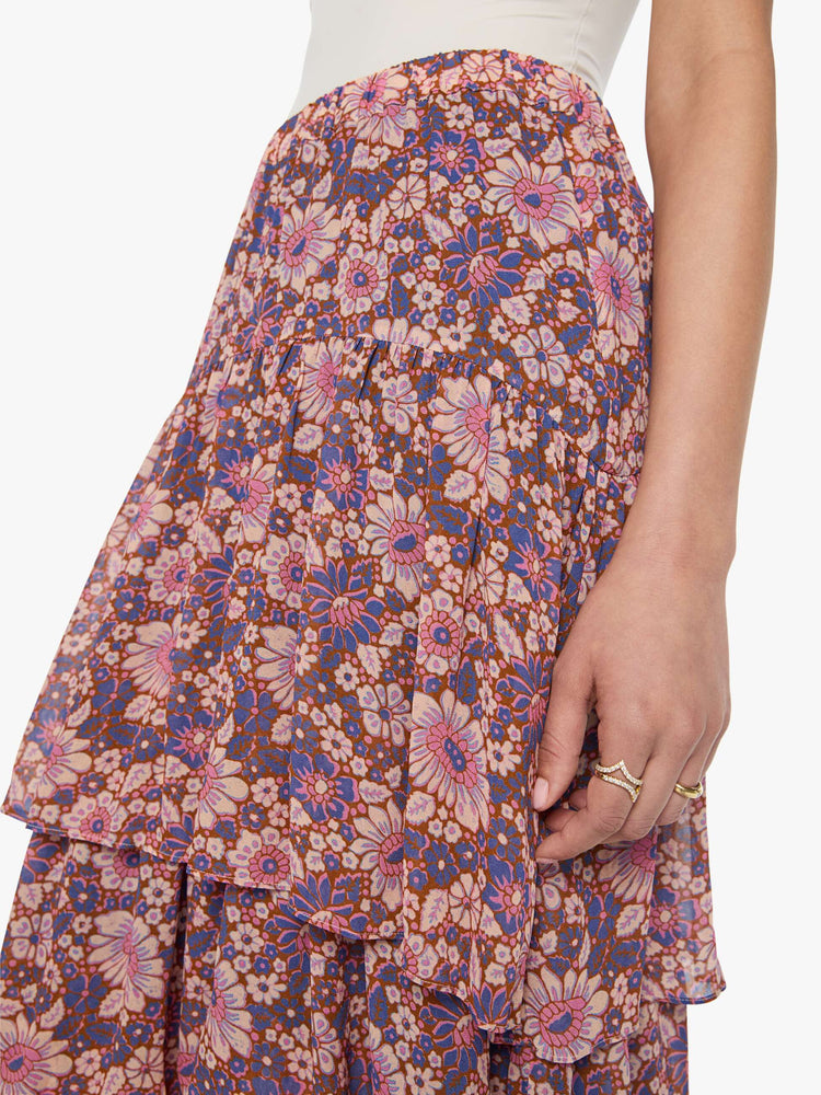 Close up view of a woman in a warm-toned floral print, the Gretchen skirt features a high rise, calf-grazing hem, oversized tiers and a loose, flowy fit.