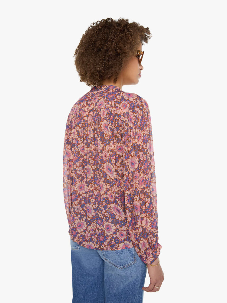 Back view of a woman in warm-toned floral print button up top with a V-neck, long balloon sleeves and curved hem with a light and airy fit.