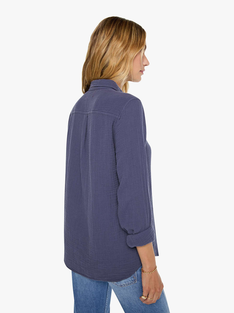 Back view of a woman in charcoal blue long-sleeve shirt features a V-neck and curved hem with a light and airy fit.