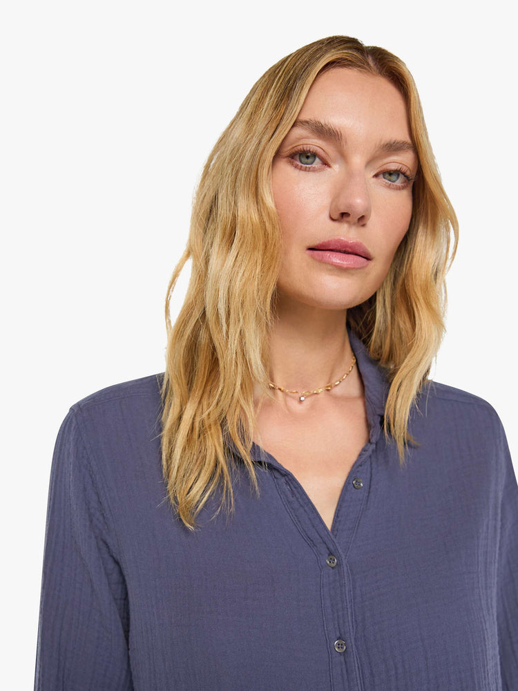 Clos up view of a woman in charcoal blue long-sleeve shirt features a V-neck and curved hem with a light and airy fit.