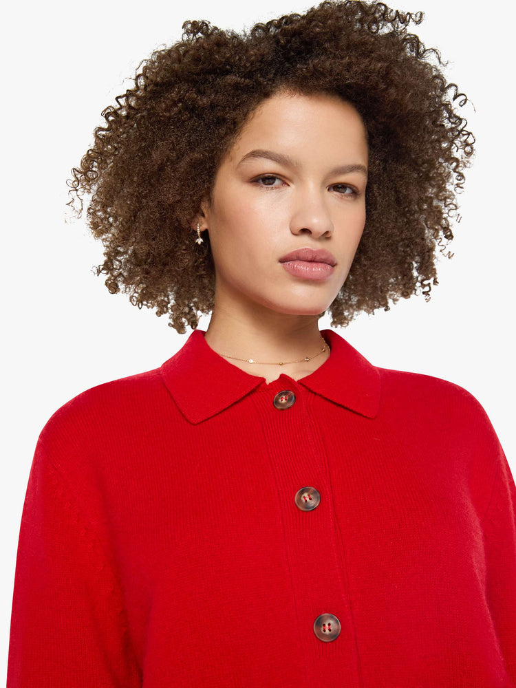 Front close up view of a bright red knit cardigan featuring front pockets, a cropped body and collar.
