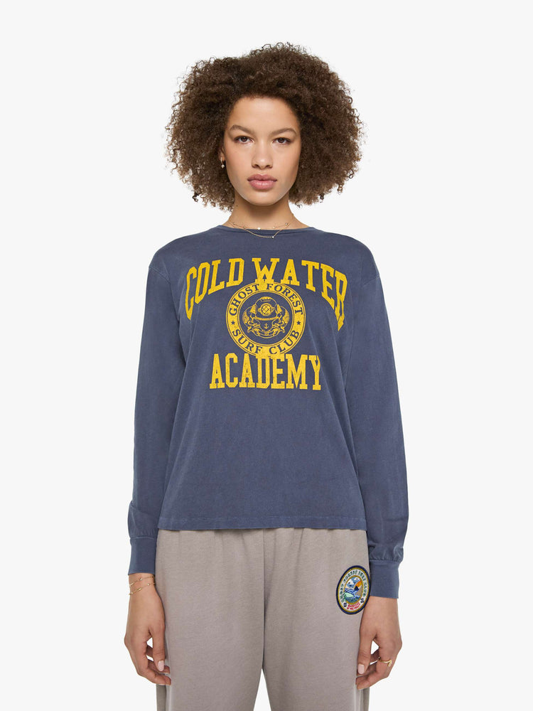 Front view of a woman in a tee is designed in a sun-faded navy with the brand's logo and text in yellow on the chest.