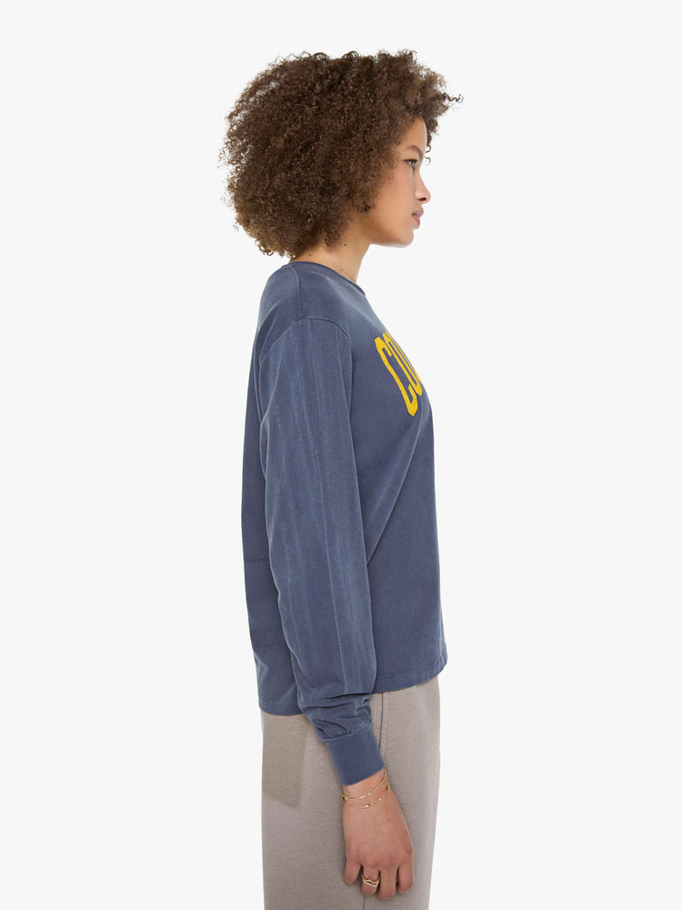 Side view of a woman in a tee is designed in a sun-faded navy with the brand's logo and text in yellow on the chest.