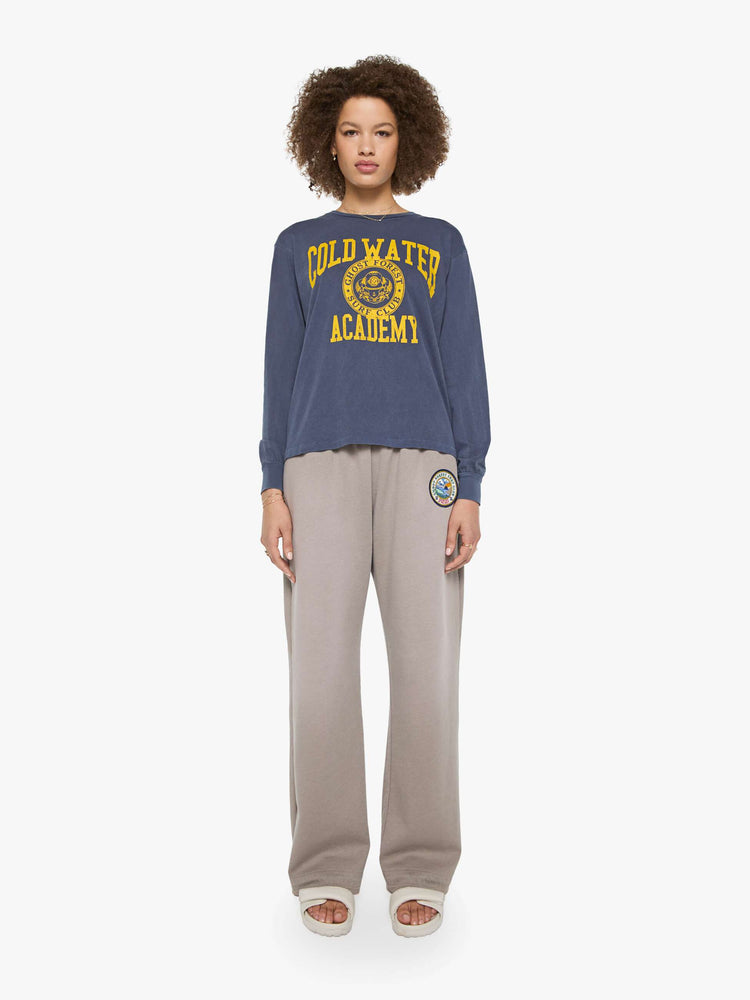 Full body view of a woman in a tee is designed in a sun-faded navy with the brand's logo and text in yellow on the chest.