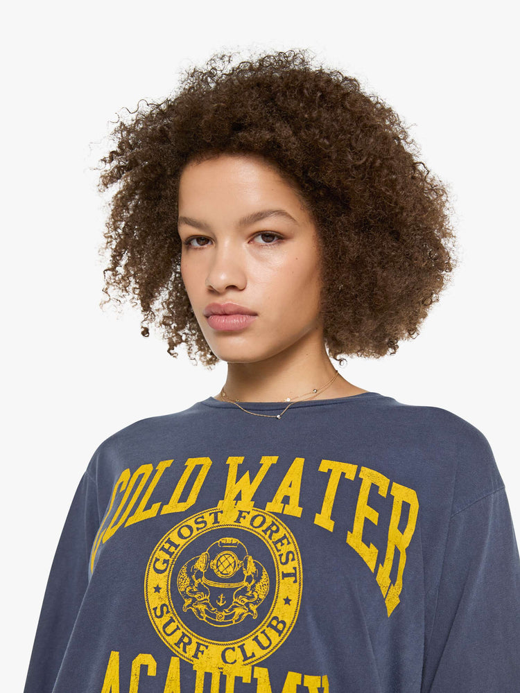 Close up view of a woman in a tee is designed in a sun-faded navy with the brand's logo and text in yellow on the chest.