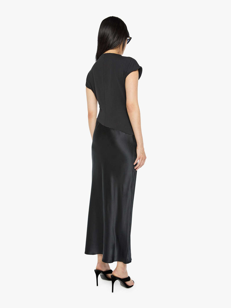 Back view of a woman in a black dress with a boat neck, short sleeves, a narrow fit and an ankle-length hem.