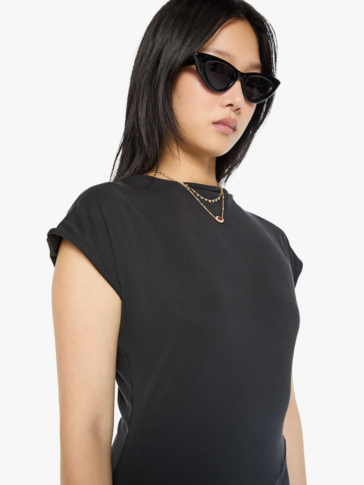 Close up top view of a woman in a black dress with a boat neck, short sleeves, a narrow fit and an ankle-length hem.