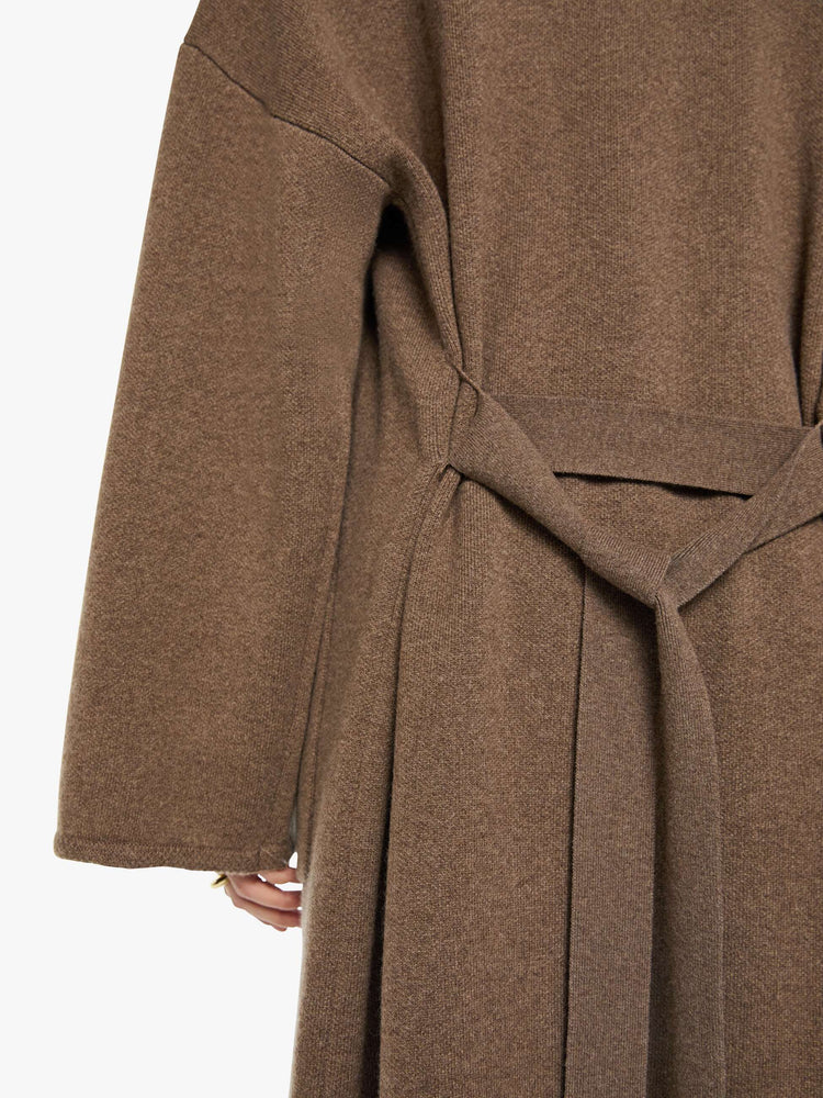 Close up view of a woman in a chocolate brown trench coat with an oversized collar, drop shoulders, a tied waist and calf-length hem.