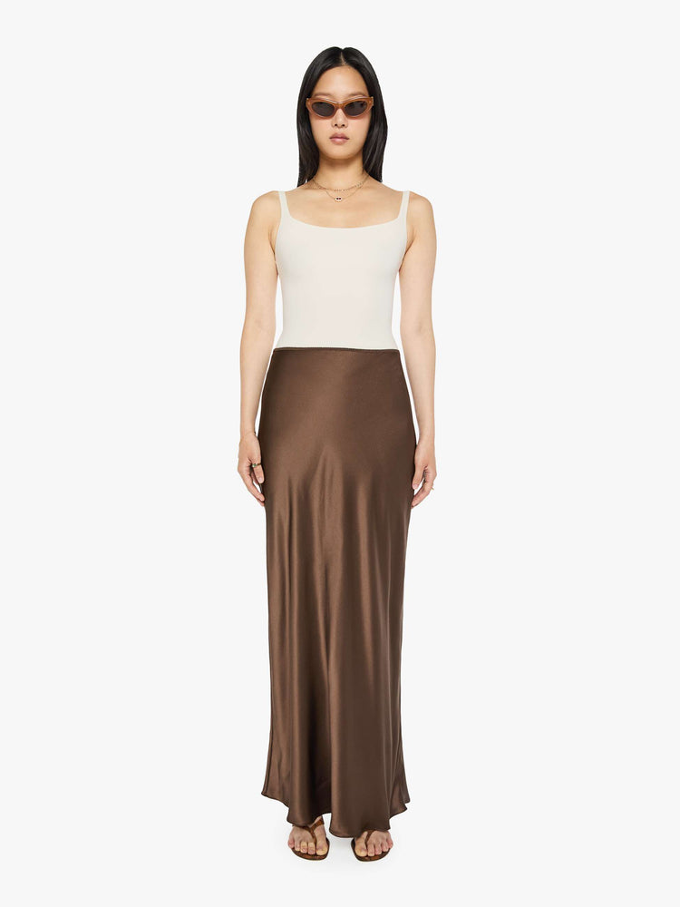 Front view of a woman in a brown low-rise maxi skirt is designed with a straight fit and a flowy, floor-length hem.