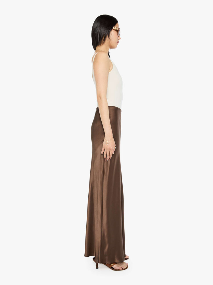 Side view of a woman in a brown low-rise maxi skirt is designed with a straight fit and a flowy, floor-length hem.
