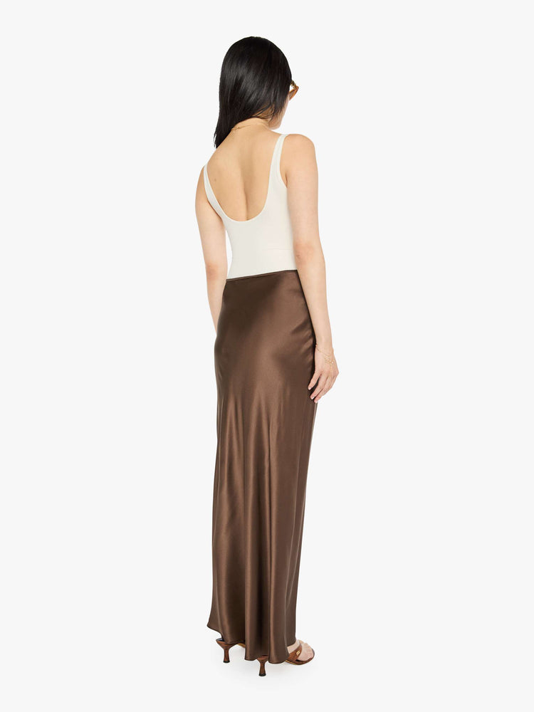 Back view of a woman in a brown low-rise maxi skirt is designed with a straight fit and a flowy, floor-length hem.
