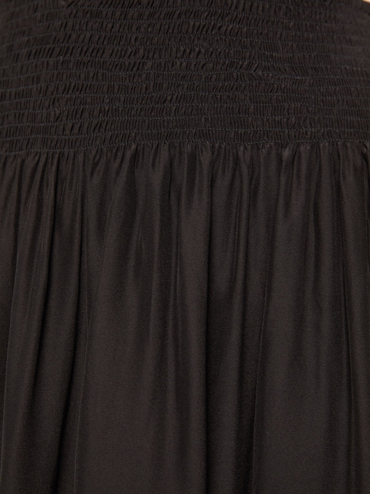 Close up swatch detail view of a black skirt featuring a wide elastic waist and full skirt.