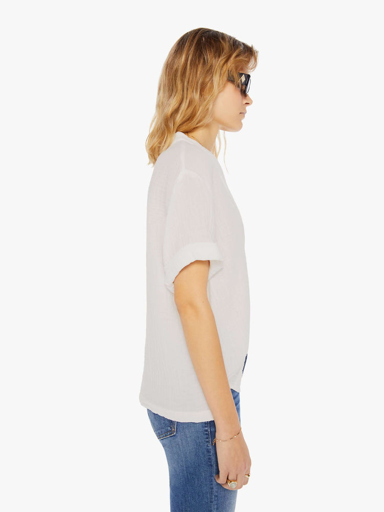 Side view of a womens cream blouse featuring a deep v neck and cuffed short sleeves.