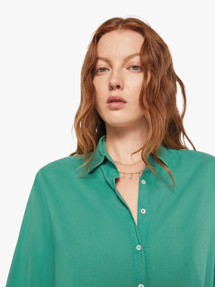 Close up view of woman in a  green button-down long sleeve shirt.