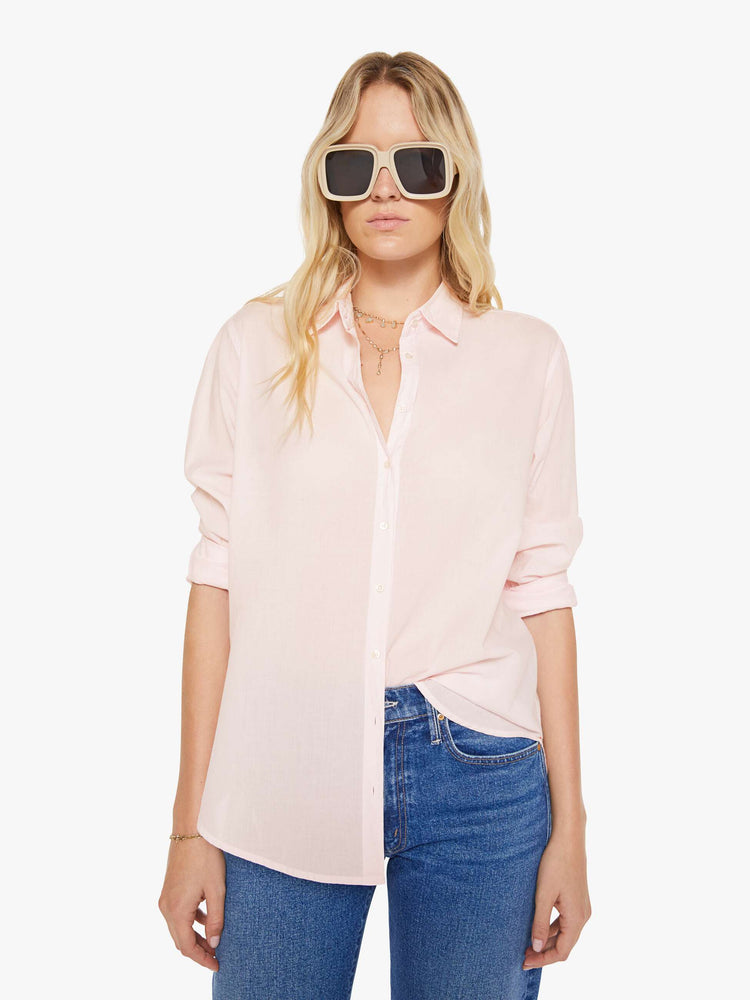 Front view of woman in a baby pink button-down long sleeve shirt.