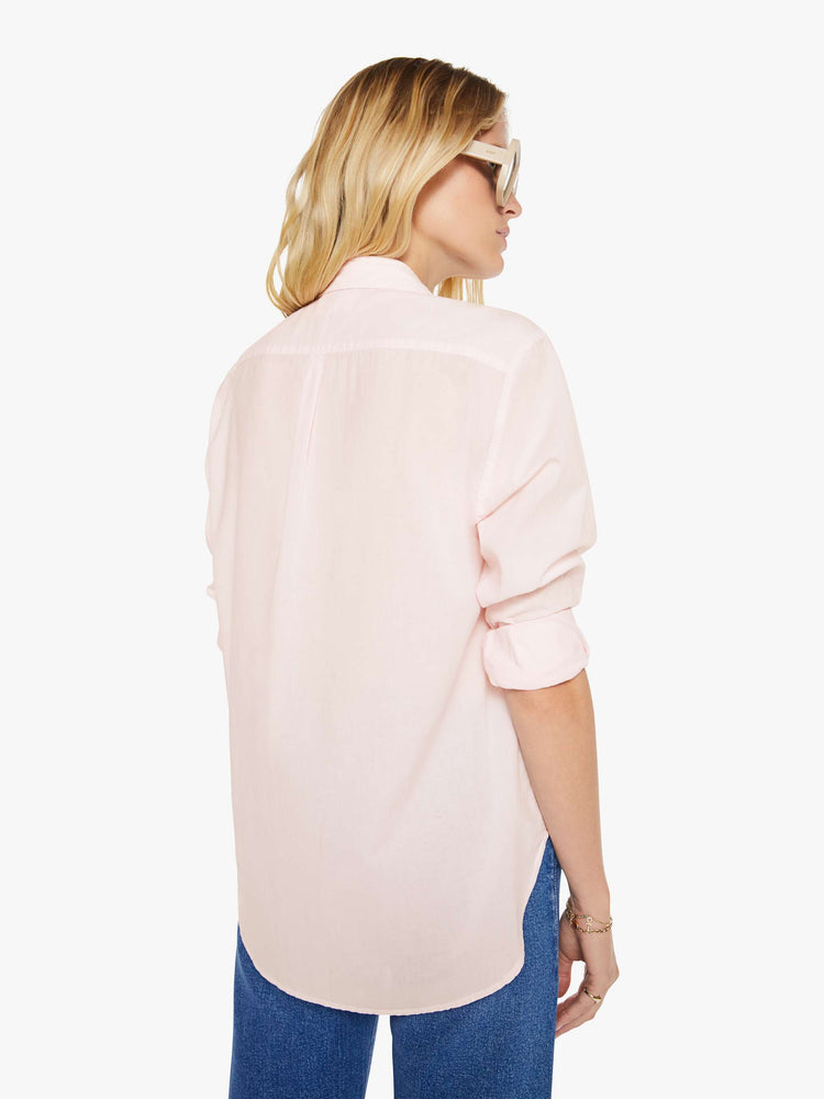 Back view of woman in a baby pink button-down long sleeve shirt.