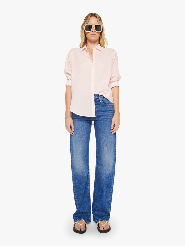 Full body view of woman in a baby pink button-down long sleeve shirt.