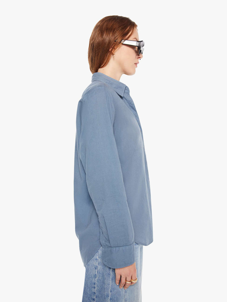 Side view of a woman in a grey-blue button-down shirt.