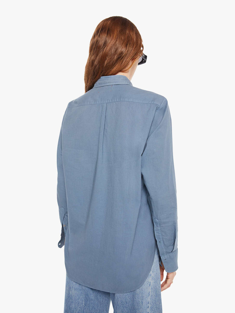 Back view of a woman in a grey-blue button-down shirt.