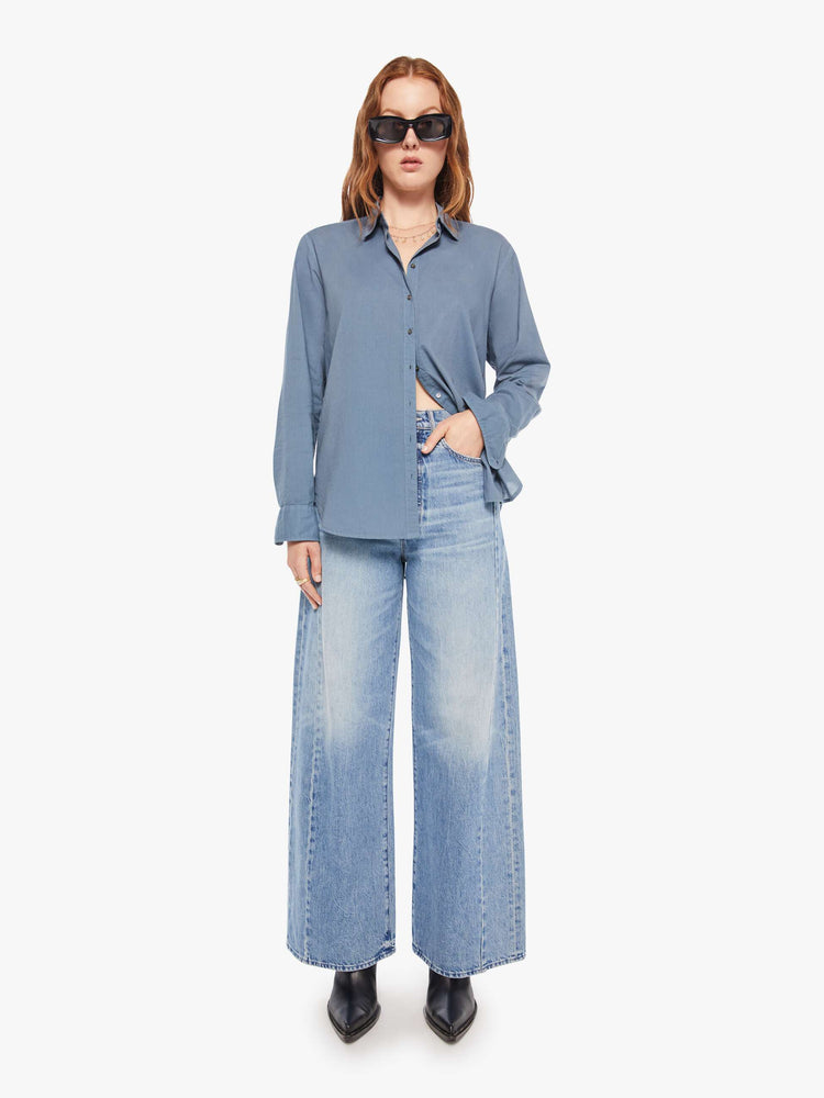 Full body view of a woman in a grey-blue button-down shirt.