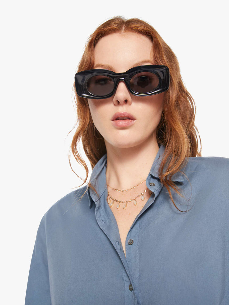 Close up view of a woman in a grey-blue button-down shirt.