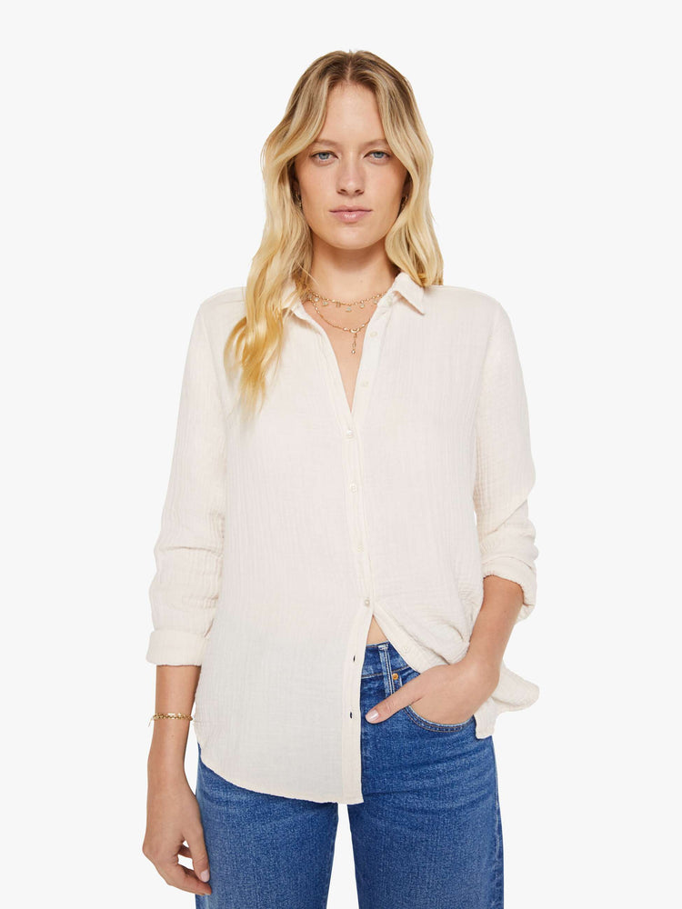 Front view of a woman in a long sleeve off-white button-down.