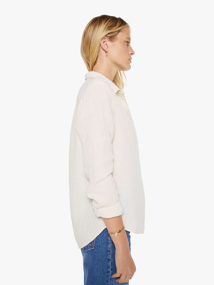 Side view of a woman in a long sleeve off-white button-down.