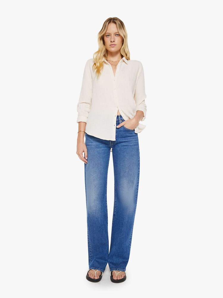 Full body view of a woman in a long sleeve off-white button-down.