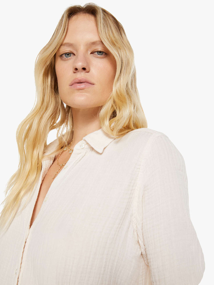 Close up view of a woman in a long sleeve off-white button-down.