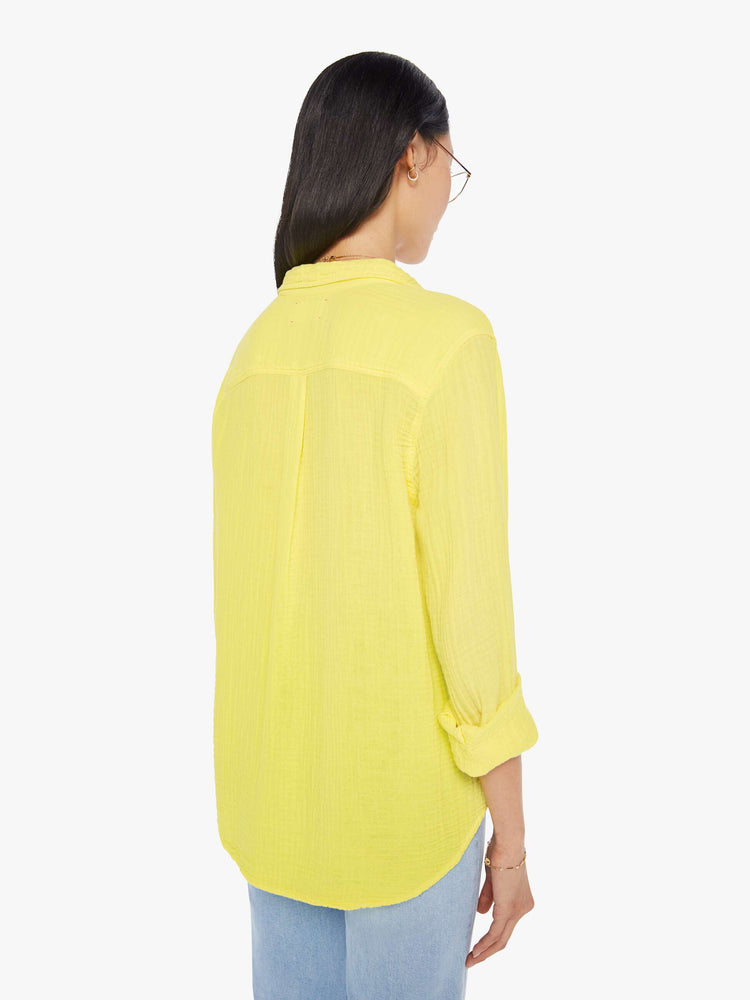 Back view of a womens bright yellow button down long sleeve shirt with a curved hem.