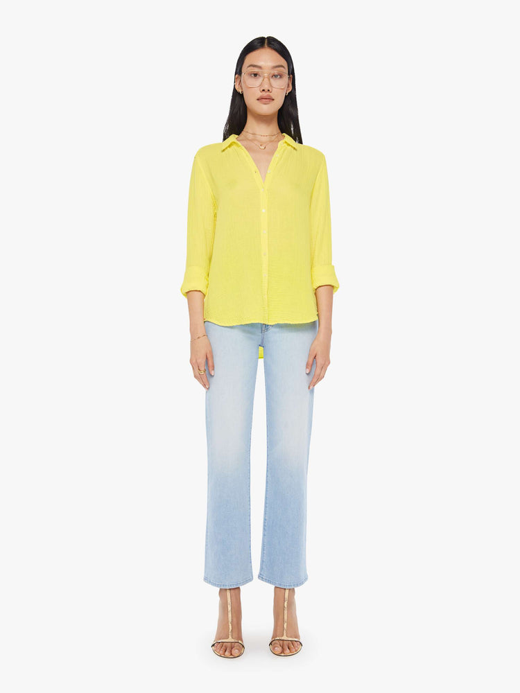 Front full body view of a womens bright yellow button down long sleeve shirt with a curved hem.