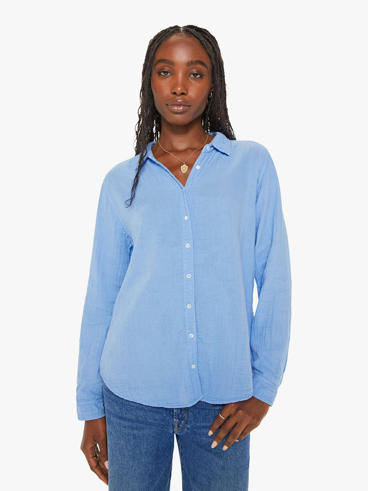Front view of a woman blue button down long sleeve in a V-neck and curved hem with a light and airy fit.