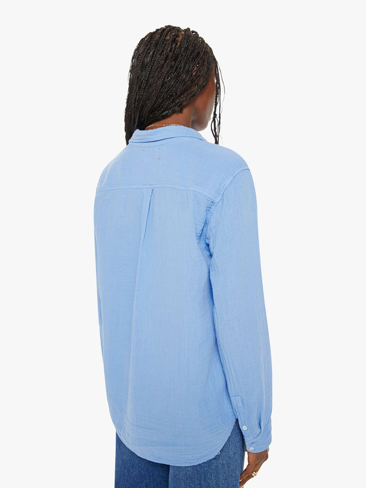 Back view of a woman blue button down long sleeve in a V-neck and curved hem with a light and airy fit.