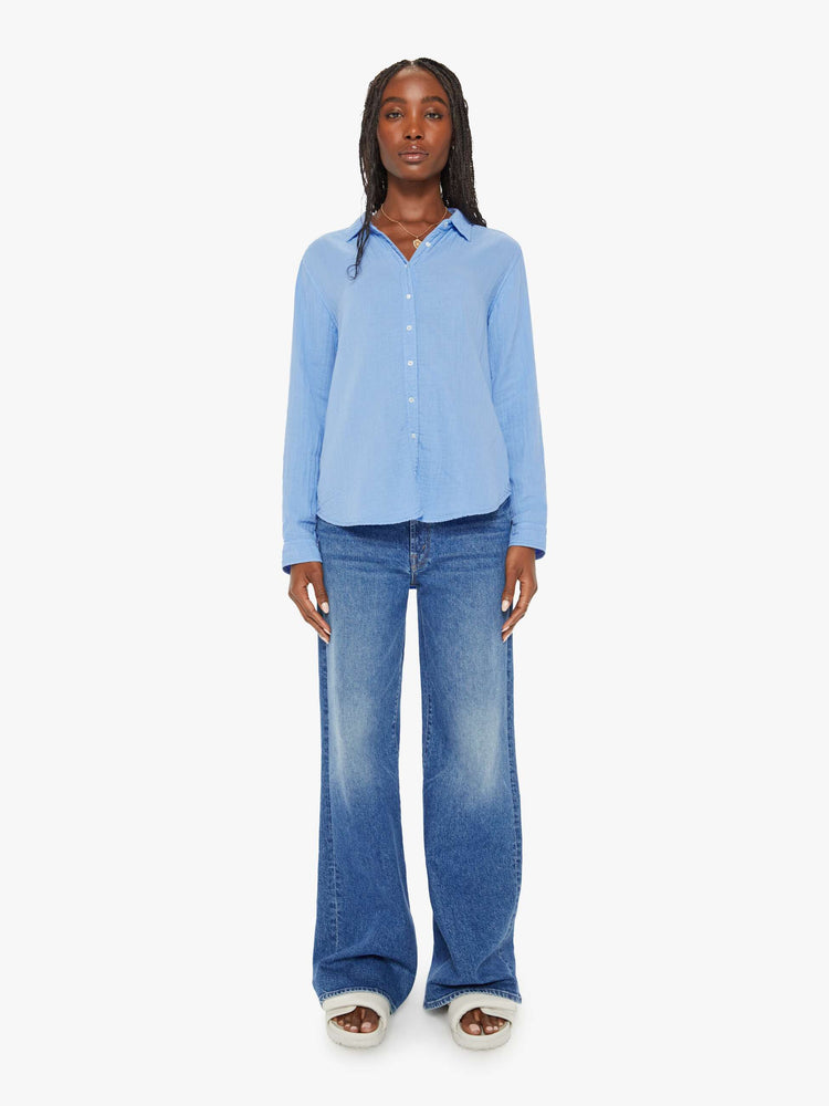 Full body view of a woman blue button down long sleeve in a V-neck and curved hem with a light and airy fit.