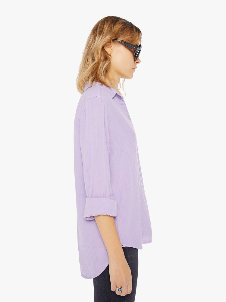 Side view of a womens light purple button down long sleeve shirt with a curved hem.