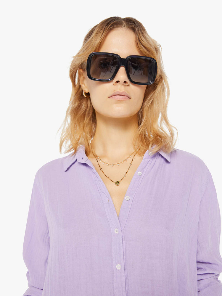 Front close up view of a womens light purple button down long sleeve shirt with a curved hem.