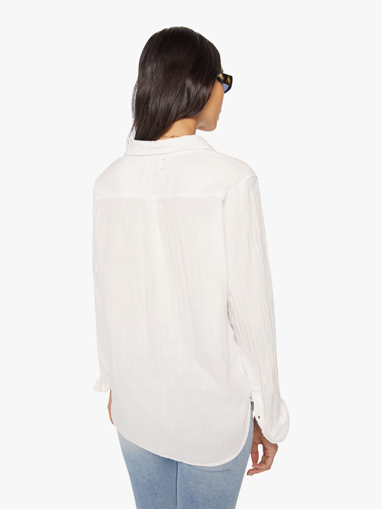Back view of a woman white button-down features a V-neck and curved hem with a light and airy fit.
