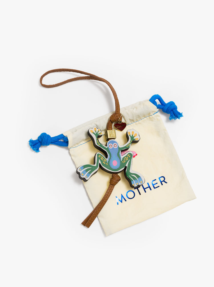 A tan bag charm made from 100% leather with a heart charm, M bead and a colorful 2.7 x 2.8-inch frog at the end on top of a bag.