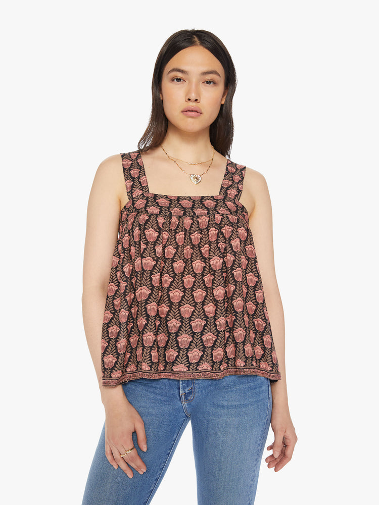 Front view of a woman top designed in brown with a baby pink tulip print, and features detailed straps and buttons in the back.